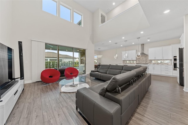 living room with light hardwood / wood-style floors and a towering ceiling