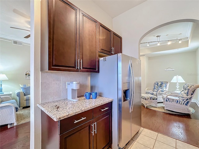 kitchen featuring light tile patterned floors, ceiling fan, backsplash, stainless steel refrigerator with ice dispenser, and light stone counters