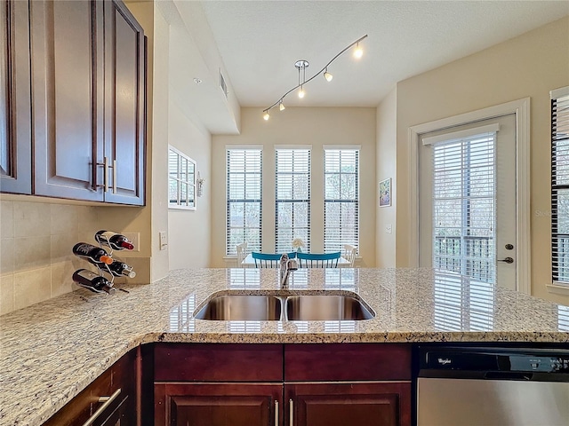 kitchen with sink, tasteful backsplash, kitchen peninsula, dishwasher, and light stone countertops