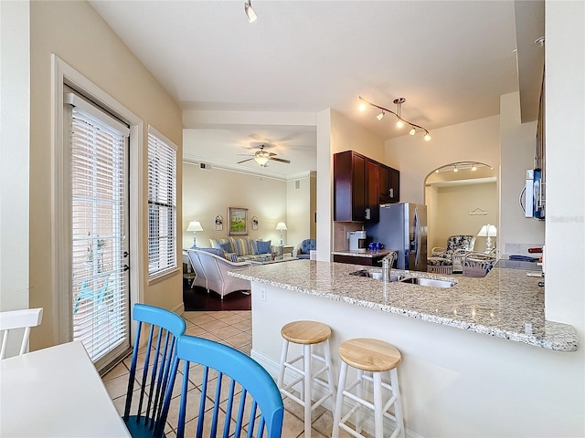 kitchen with appliances with stainless steel finishes, kitchen peninsula, sink, and light tile patterned floors