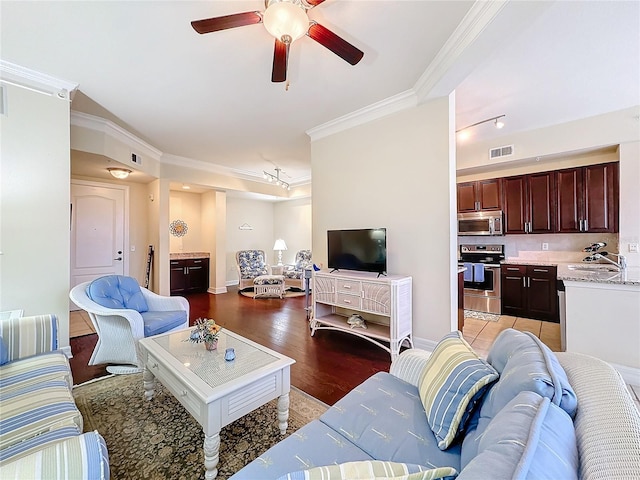 living room with sink, crown molding, ceiling fan, and light wood-type flooring