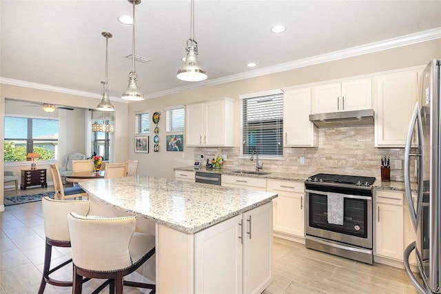 kitchen featuring sink, appliances with stainless steel finishes, hanging light fixtures, a center island, and white cabinets