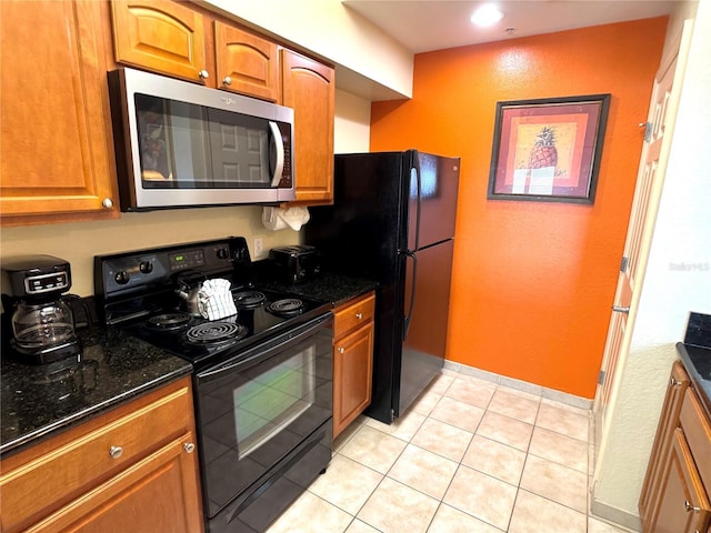 kitchen featuring light tile patterned flooring, dark stone counters, and black appliances