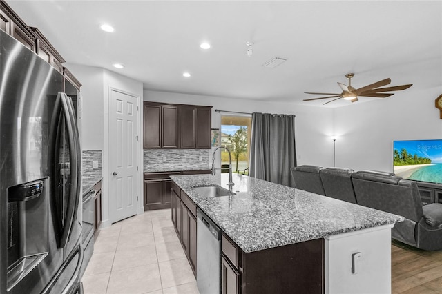 kitchen with dark brown cabinetry, sink, tasteful backsplash, an island with sink, and stainless steel appliances