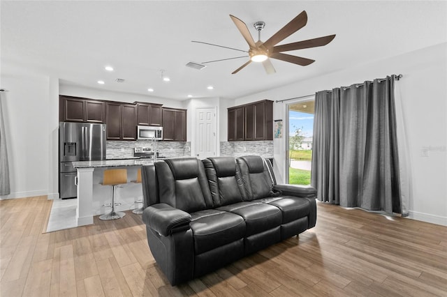 living room with ceiling fan and light hardwood / wood-style flooring