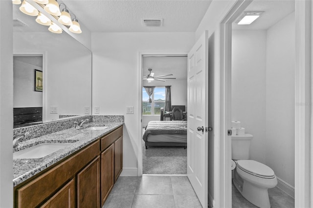 bathroom featuring tile patterned flooring, vanity, ceiling fan, toilet, and a textured ceiling