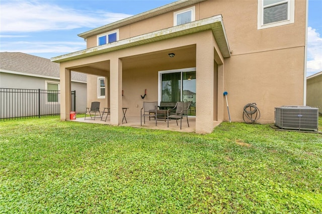 rear view of house with cooling unit, a lawn, and a patio