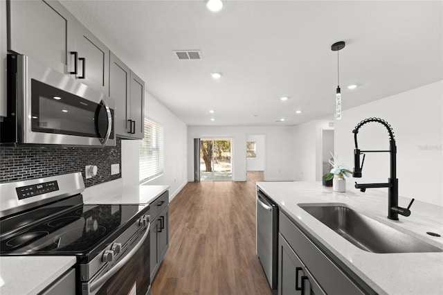 kitchen with sink, tasteful backsplash, decorative light fixtures, appliances with stainless steel finishes, and gray cabinets