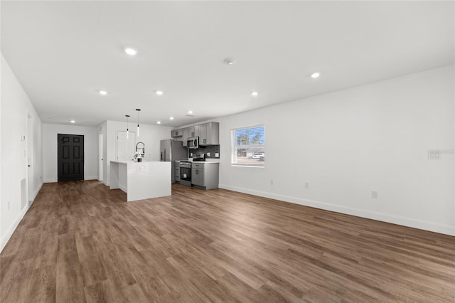 unfurnished living room with sink and hardwood / wood-style floors