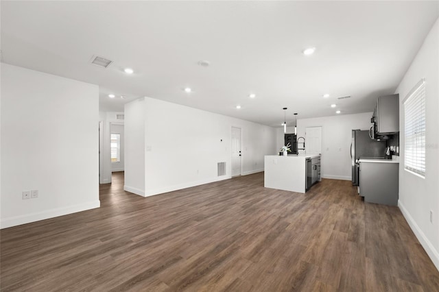 kitchen featuring a kitchen island with sink, pendant lighting, plenty of natural light, and dark hardwood / wood-style floors