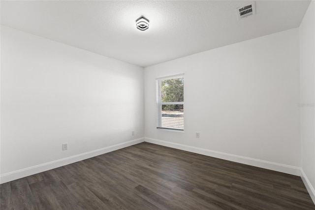 spare room with a textured ceiling and dark hardwood / wood-style flooring