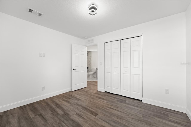 unfurnished bedroom featuring dark wood-type flooring, a textured ceiling, and a closet