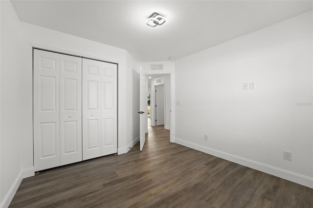 unfurnished bedroom with dark hardwood / wood-style flooring, a closet, and a textured ceiling