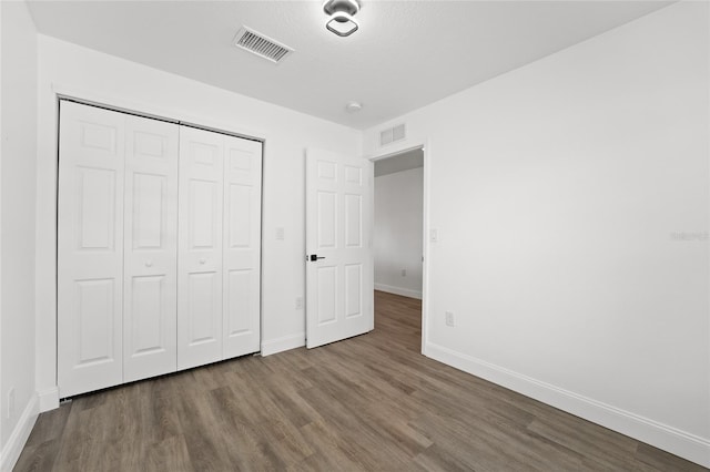 unfurnished bedroom with hardwood / wood-style flooring and a closet