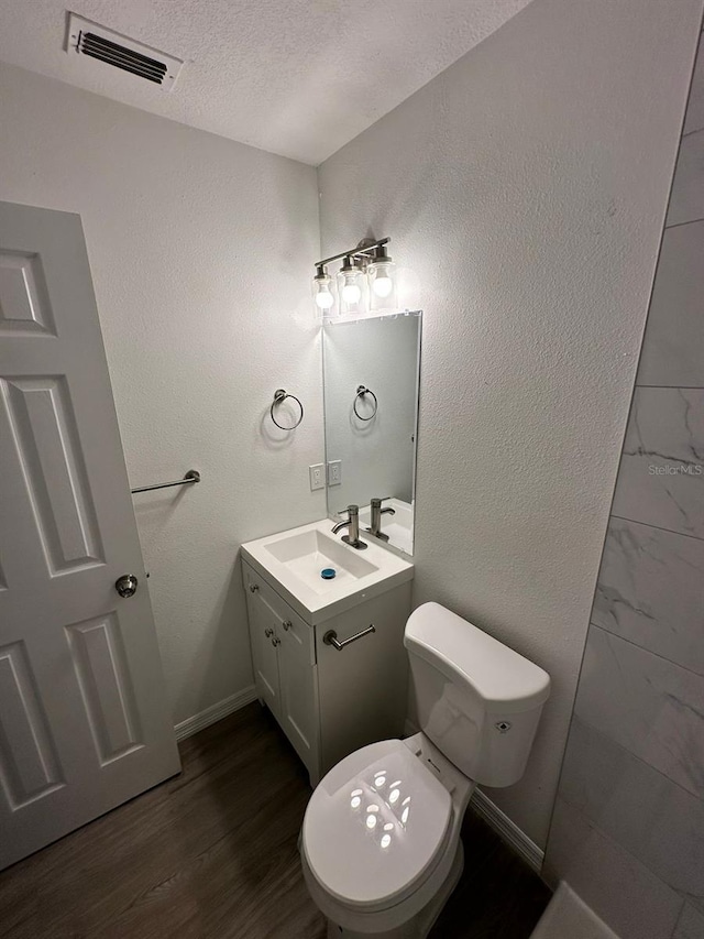 bathroom with vanity, hardwood / wood-style floors, toilet, and a textured ceiling