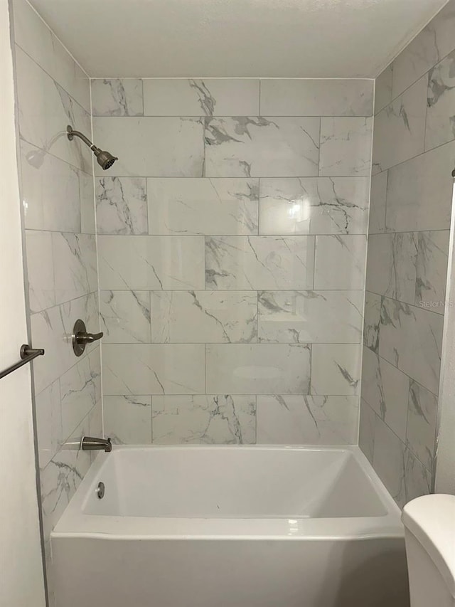 bathroom with tiled shower / bath and toilet