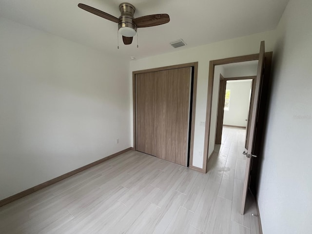 unfurnished bedroom featuring light hardwood / wood-style floors, ceiling fan, and a closet