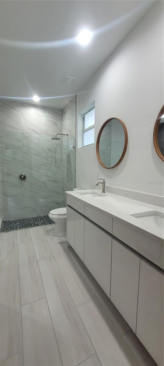 bathroom featuring tiled shower, vanity, and toilet