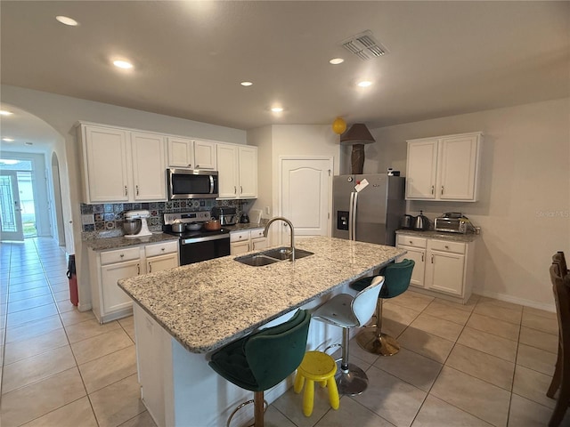 kitchen featuring sink, appliances with stainless steel finishes, white cabinetry, a kitchen breakfast bar, and an island with sink