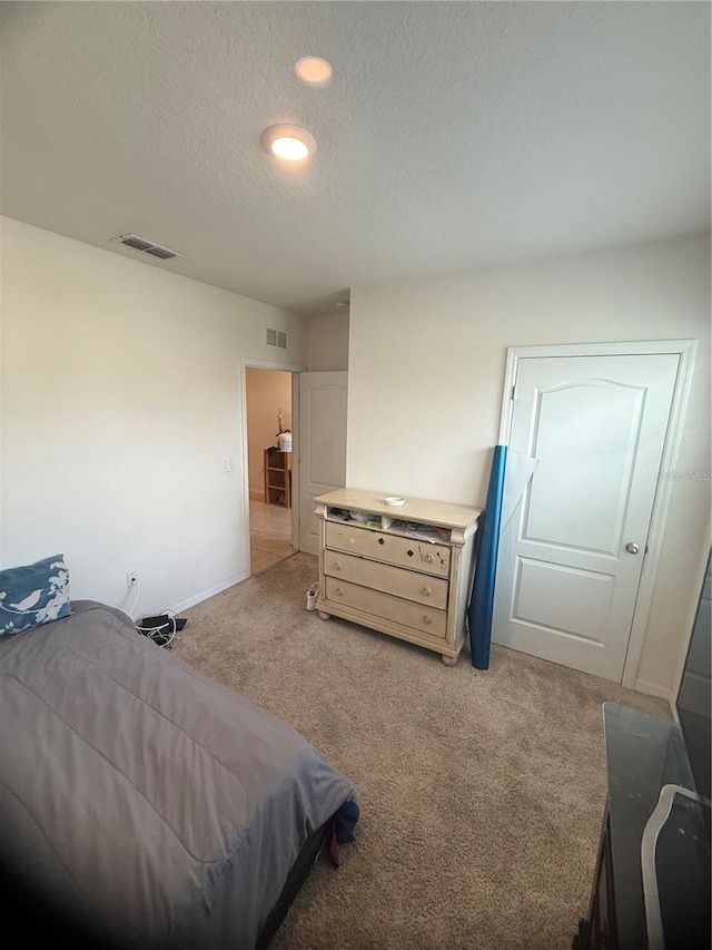 bedroom with light carpet and a textured ceiling