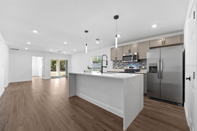 kitchen with sink, hanging light fixtures, a kitchen island with sink, stainless steel appliances, and dark wood-type flooring