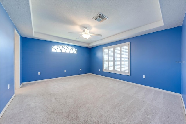 carpeted empty room with ceiling fan, a raised ceiling, and a textured ceiling