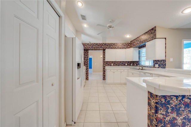 kitchen featuring tile countertops, white cabinets, white fridge with ice dispenser, light tile patterned floors, and ceiling fan