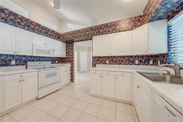 kitchen featuring white cabinetry, sink, white appliances, and light tile patterned flooring