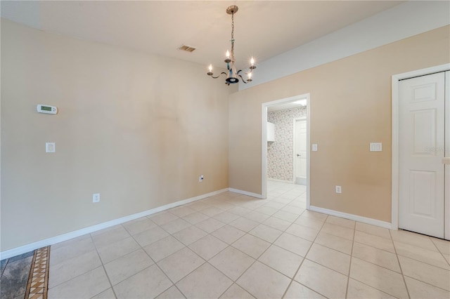 empty room featuring light tile patterned flooring and a chandelier