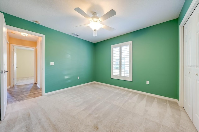 unfurnished bedroom with light colored carpet, ceiling fan, and a closet