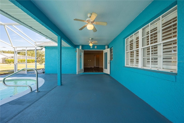 view of patio with ceiling fan and glass enclosure