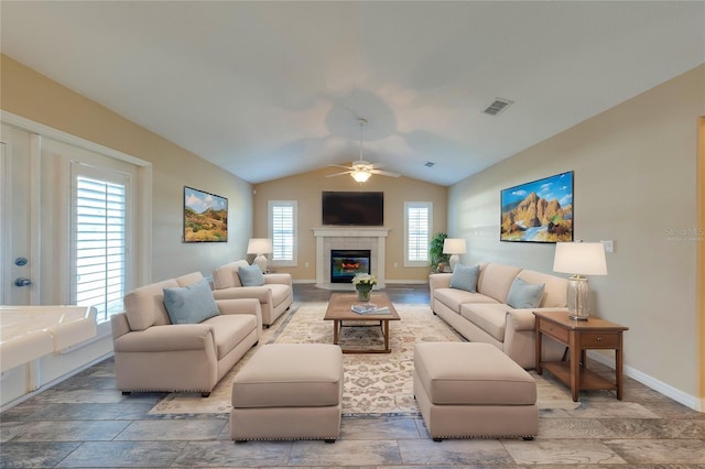 living room with lofted ceiling, a tiled fireplace, plenty of natural light, and ceiling fan