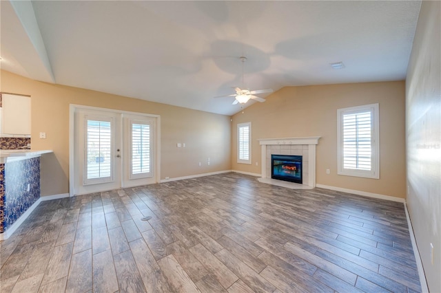 unfurnished living room with lofted ceiling, hardwood / wood-style floors, a tile fireplace, and ceiling fan