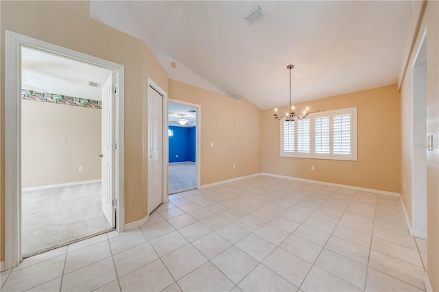 empty room with vaulted ceiling, light tile patterned floors, and a chandelier