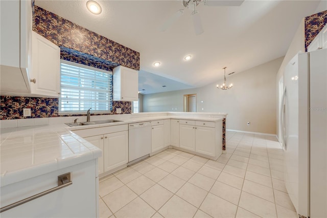 kitchen featuring tile countertops, white cabinetry, sink, kitchen peninsula, and white appliances