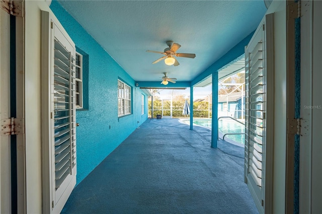 view of patio featuring ceiling fan and glass enclosure