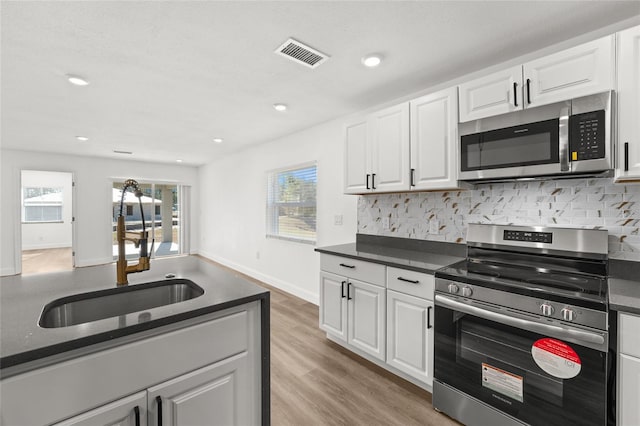 kitchen with white cabinetry, sink, backsplash, and appliances with stainless steel finishes