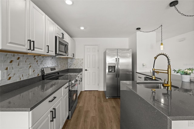 kitchen with sink, appliances with stainless steel finishes, hanging light fixtures, dark hardwood / wood-style floors, and white cabinets