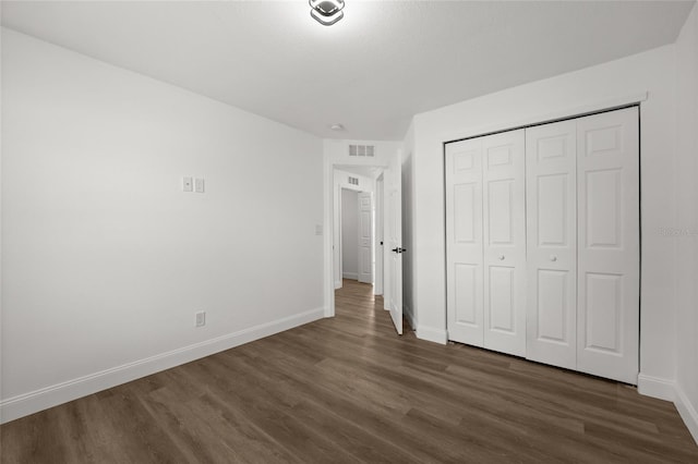 unfurnished bedroom with dark hardwood / wood-style flooring and a closet