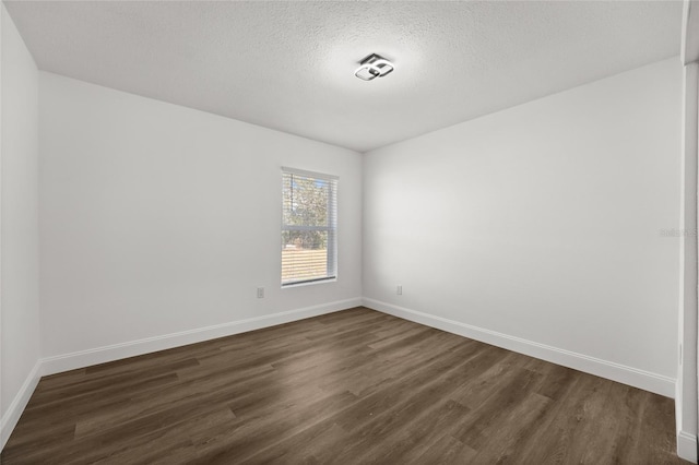 empty room featuring dark hardwood / wood-style floors and a textured ceiling