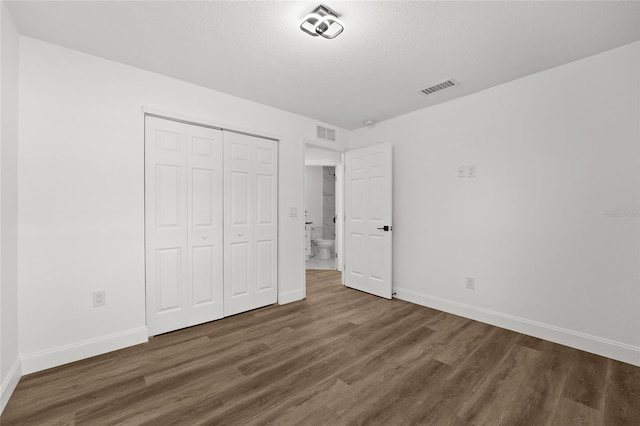 unfurnished bedroom featuring dark hardwood / wood-style floors, a closet, and a textured ceiling