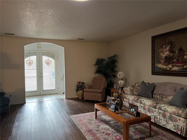 living room featuring wood-type flooring, french doors, and a textured ceiling