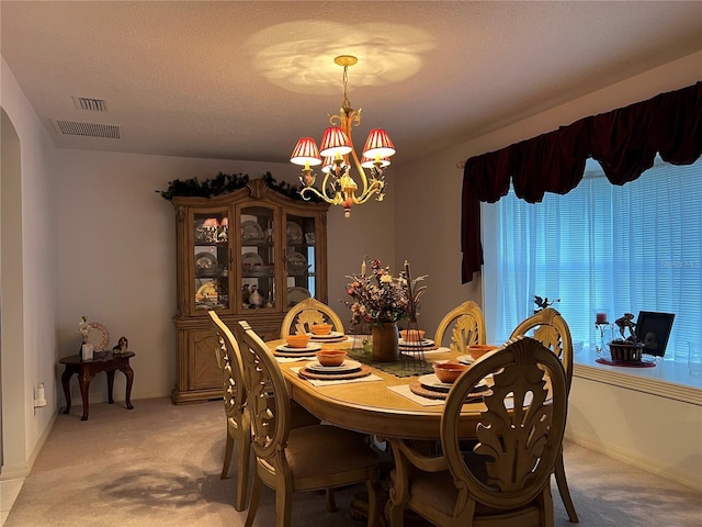 dining space featuring light carpet, a notable chandelier, and a textured ceiling