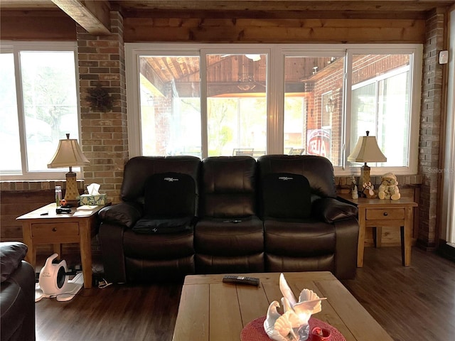 living room with brick wall, a wealth of natural light, and dark hardwood / wood-style flooring