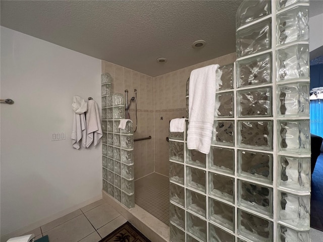 bathroom with a textured ceiling, tile patterned floors, and tiled shower