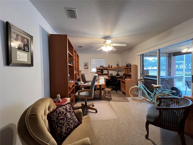 carpeted office space featuring ceiling fan and a textured ceiling