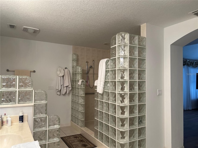 bathroom featuring vanity, tile patterned floors, a textured ceiling, and walk in shower