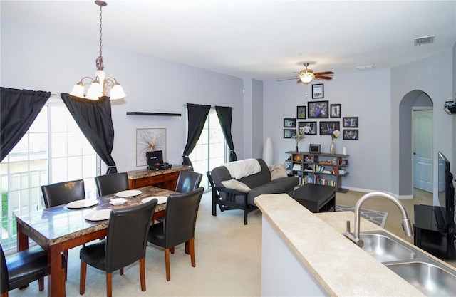 dining space featuring sink and ceiling fan with notable chandelier