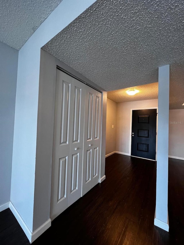 hallway with a textured ceiling and dark hardwood / wood-style flooring