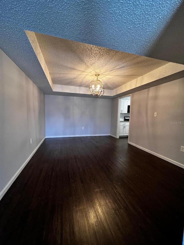 empty room featuring dark hardwood / wood-style floors, a chandelier, and a textured ceiling